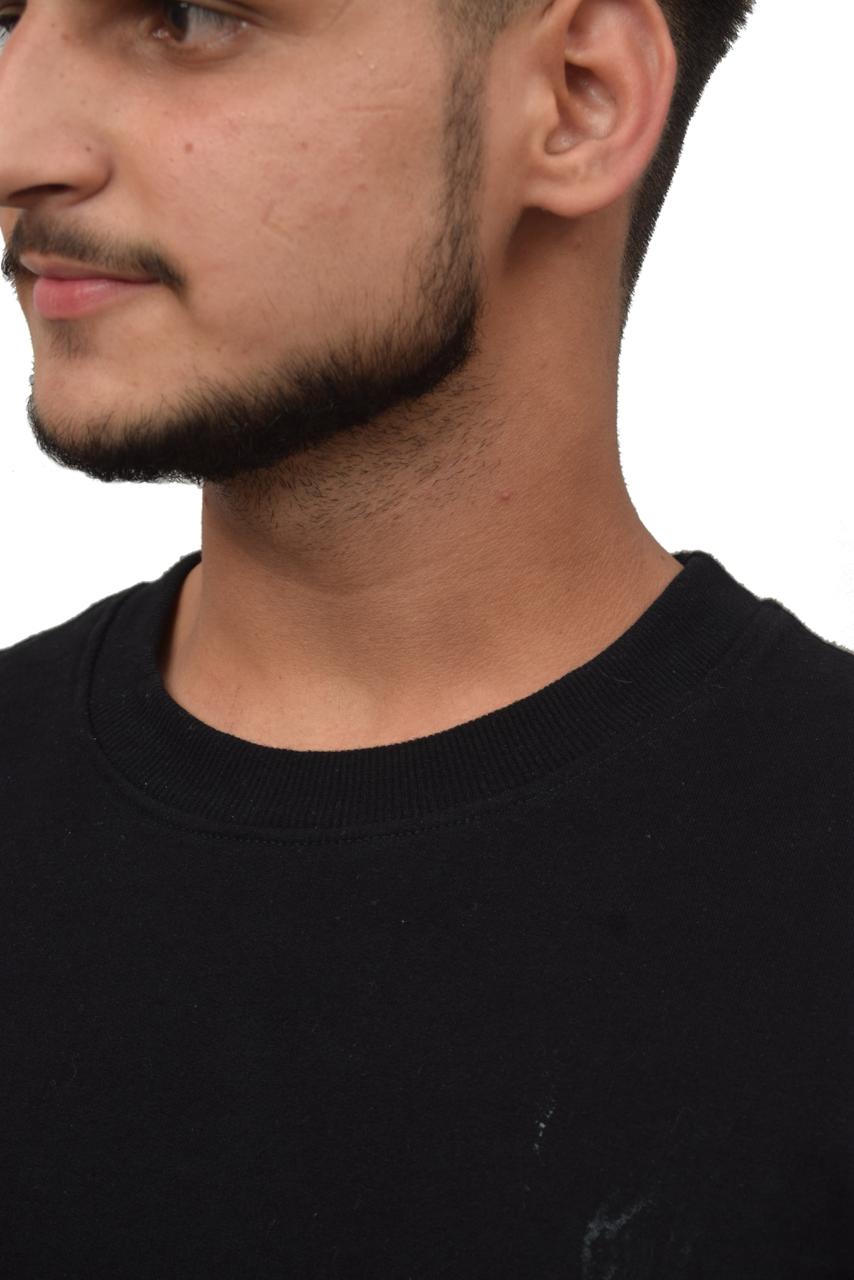 Close-up of a person wearing a black shirt with a plain background